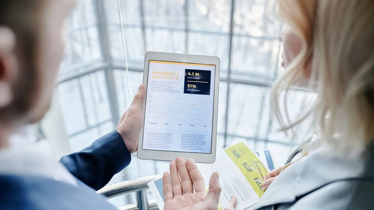 Zwei Personen im Büro schauen gemeinsam auf eine Geschäftsapp auf dem Tablet
